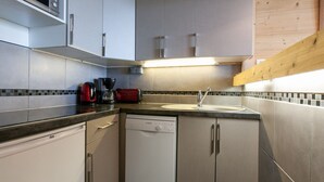 Une cuisine compacte équipée d’appareils électroménagers en acier inoxydable, d’un lave-vaisselle et d’un four à micro-ondes.