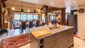 A spacious kitchen with a central island, wooden beams, and a dining area with a view.