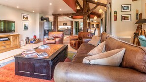A spacious living room with leather sofas, a wooden coffee table, and a fireplace.