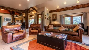 A spacious living room with leather sofas, a coffee table, and pendant lighting.