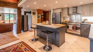 A modern kitchen with a central island, stainless steel appliances, and a rustic wooden ceiling.