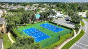 Una pista de tennis envoltada de verdura i edificis residencials.