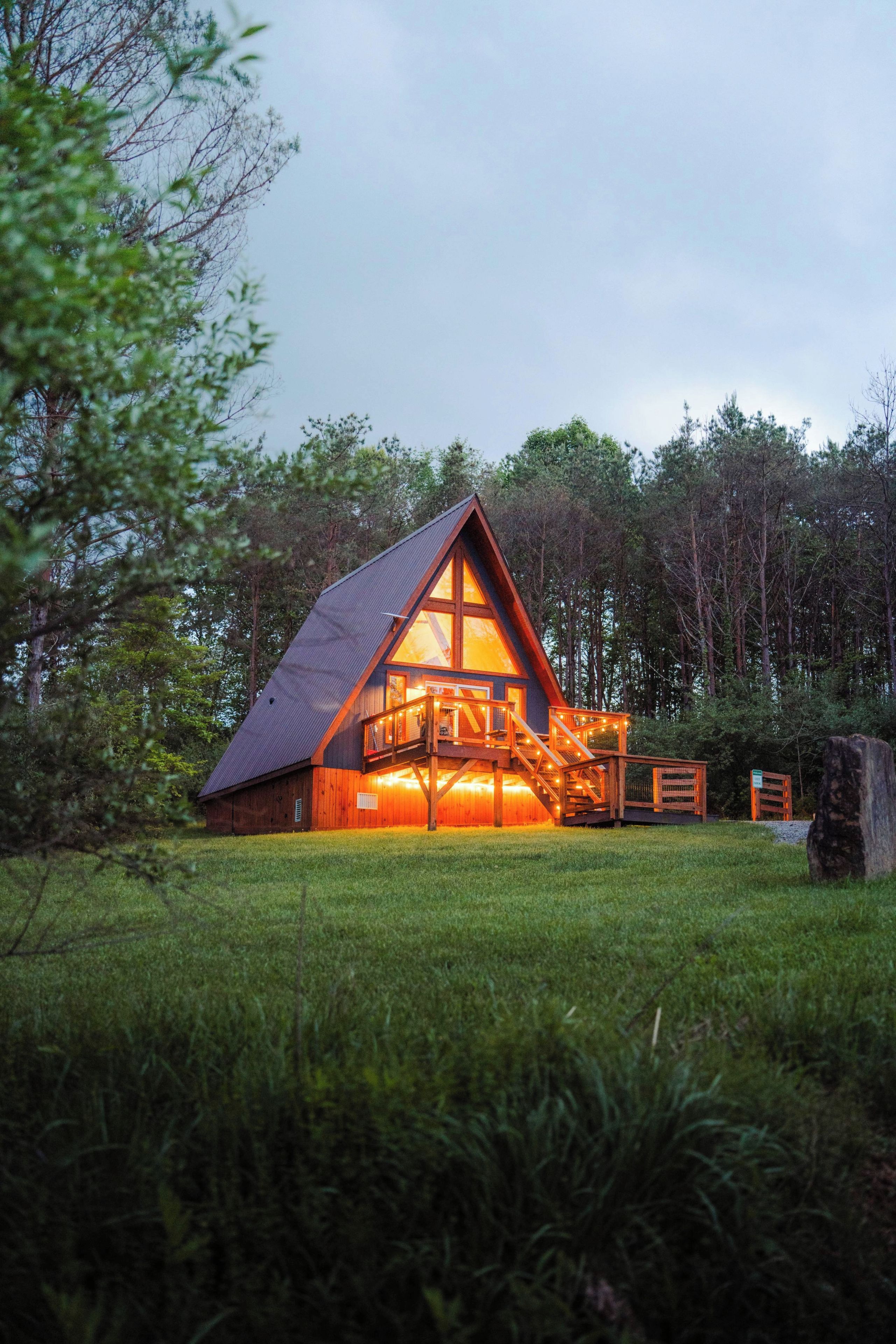 Une cabane avec un toit en pente, une terrasse en bois et un escalier menant à un porche.