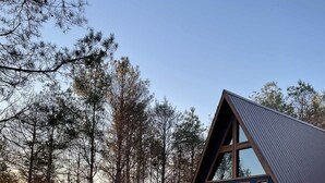 Una baita con una scala in legno che conduce a un patio, circondata da alberi.