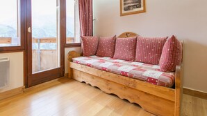 A cozy room with a wooden bench bed, large windows, and a framed picture on the wall.