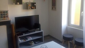 Una sala de estar con televisor de pantalla plana, estantes con adornos, una mesa de centro y una ventana con vistas.