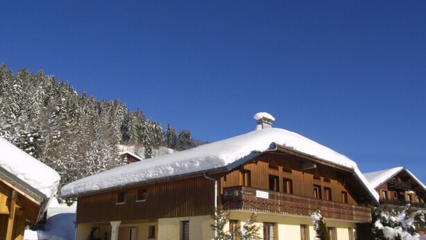 A wooden chalet with a snow-covered roof, surrounded by snow and trees. - Charming 2-Bed Apartment, Wi-Fi, Near Ski Lifts & Center, Les Gets (Les Gets)