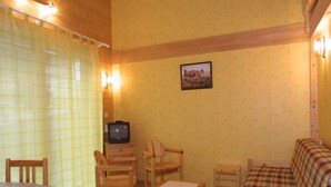 A cozy room with a bed, a sofa, a television, and a small table. - Charming 2-Bed Apartment, Wi-Fi, Near Ski Lifts & Center, Les Gets (Les Gets)