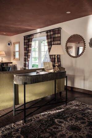 A room with a sofa, a table with a lamp, a mirror, and a window with curtains. - A high-design primary residence designed for slow mornings and creative resets in Page Springs. 3 king beds and pull out couch can accommodate up to 8 guests. (Cornville)