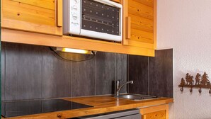 Uma cozinha compacta com armários de madeira, forno embutido, lava-louças e uma pia.