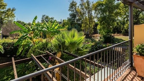 A balcony with a metal railing overlooking a garden with various plants and trees. - Luxury Beachfront Villa with Private Terrace & Pools in Puerto Banús (Marbella)
