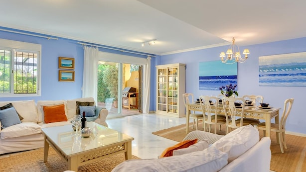 A spacious living room with a large window, a dining area, and a view of the outdoors. - Luxury Beachfront Villa with Private Terrace & Pools in Puerto Banús (Marbella)