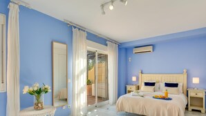 A bedroom with a bed, bedside tables, a mirror, a window with curtains, and a small table with flowers. - Luxury Beachfront Villa with Private Terrace & Pools in Puerto Banús (Marbella)