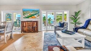 A living room with a TV, a sofa, a coffee table, and a dining area with chairs and a cabinet. - P08 - Beautiful 4 bedroom, 3 bathroom half Duplex in Key Colony with private pool (Key Colony Beach)