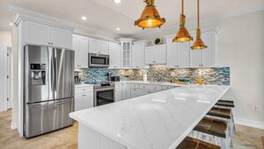 A modern kitchen with white cabinetry, stainless steel appliances, a marble island, and pendant lighting. - P08 - Beautiful 4 bedroom, 3 bathroom half Duplex in Key Colony with private pool (Key Colony Beach)