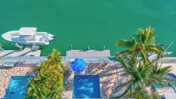 A resort with a swimming pool, lounge chairs, and a dock with boats. - P08 - Beautiful 4 bedroom, 3 bathroom half Duplex in Key Colony with private pool (Key Colony Beach)