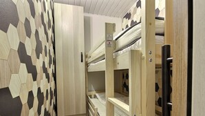 A narrow hallway with a geometric patterned wall, a bunk bed with a wooden frame, and a door with a safety sign. - Renovated studio for 4 pers at the foot of the slopes (La Plagne)
