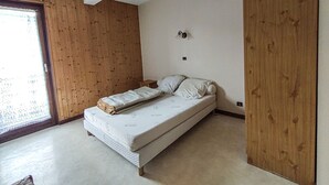 A bedroom with a single bed, wooden panel walls, a small bedside table, and a window with a view. - Large apartment for 8, pets allowed, parking, near the slopes (Les Gets)