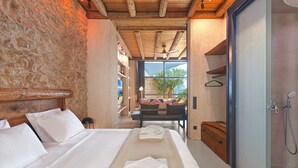 Un dormitorio con una cama grande, techo de madera, pared de piedra y vistas a un balcón con sofá.
