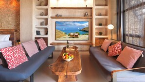 Una sala de estar acogedora con dos sofás, una mesa de centro de madera con fruta y un televisor grande en la pared.