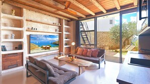 Un salón moderno con techo de madera, televisor grande, sofá y mesa de comedor.