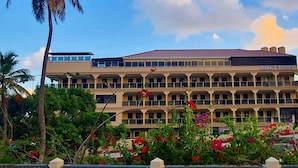 A multi-story hotel with balconies, named "MYAH'S SUITES," surrounded by lush greenery and flowering plants. - Myah's Luxury Suites Hotel (Diamond)