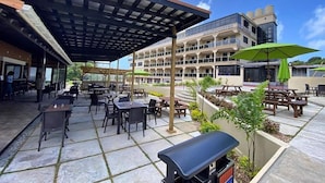 An outdoor patio area with tables and chairs, a covered seating area, and a building with 'MYAH'S SUITES' signage. - Myah's Luxury Suites Hotel (Diamond)