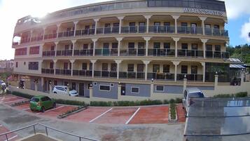 A multi-story hotel with balconies and a parking area.