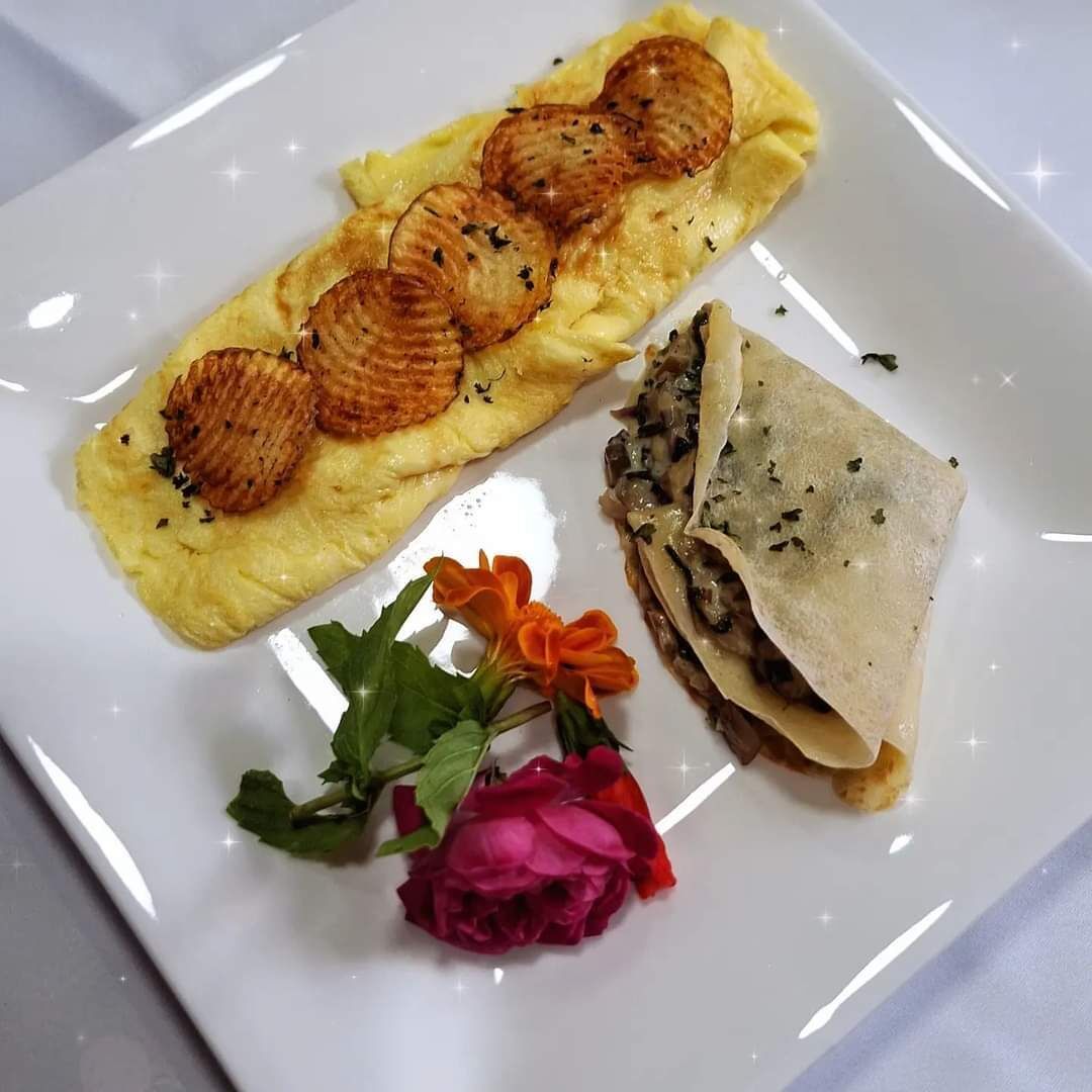 A plate with an omelette, a rolled omelette, and a flower.