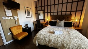 Ein Hotelzimmer mit einem Bett, einem Schreibtisch, einem Stuhl und einem an der Wand befestigten Fernseher.