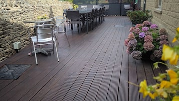 An outdoor patio with a stone wall, wooden deck, and outdoor seating area.