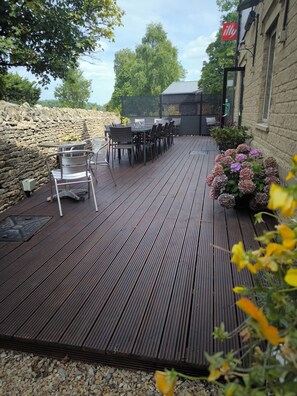 An outdoor patio with a stone wall, wooden deck, and outdoor seating area.