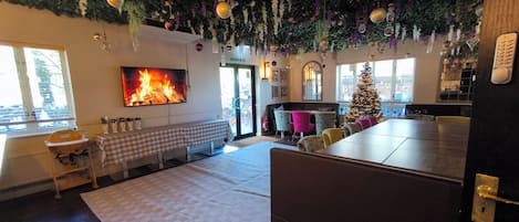A cozy room with a fireplace, a dining area, and a Christmas tree.