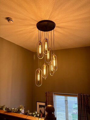 A ceiling with a circular light fixture and a window with blinds.