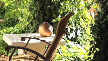A chair with a woven seat and backrest, positioned outdoors with a table and a bowl on it.