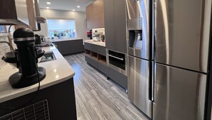 A modern kitchen with stainless steel appliances, a built-in oven, and a coffee machine. - Family Friendly Villa with Pool (Queens)