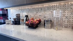 A kitchen counter with a marble backsplash, a coffee station with a kettle, a thermos, and a basket of apples. - Family Friendly Villa with Pool (Queens)