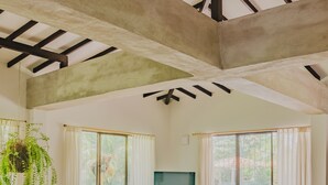 Un soggiorno spazioso con soffitto alto, ampie finestre e una televisione.