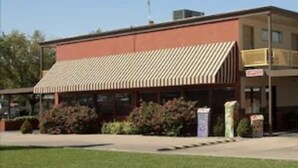 A two-story building with a flat roof and a covered front porch. - Big Bend Traveler's Inn (Great Bend)