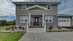 A two-story house with a front porch, a garage, and a stone retaining wall.