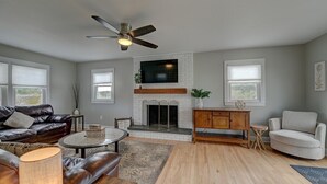 A living room with a fireplace, leather sofa, and a television mounted above it.