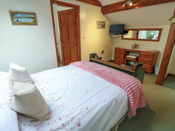 A bedroom with a bed, a dresser, a television, and a mirror.