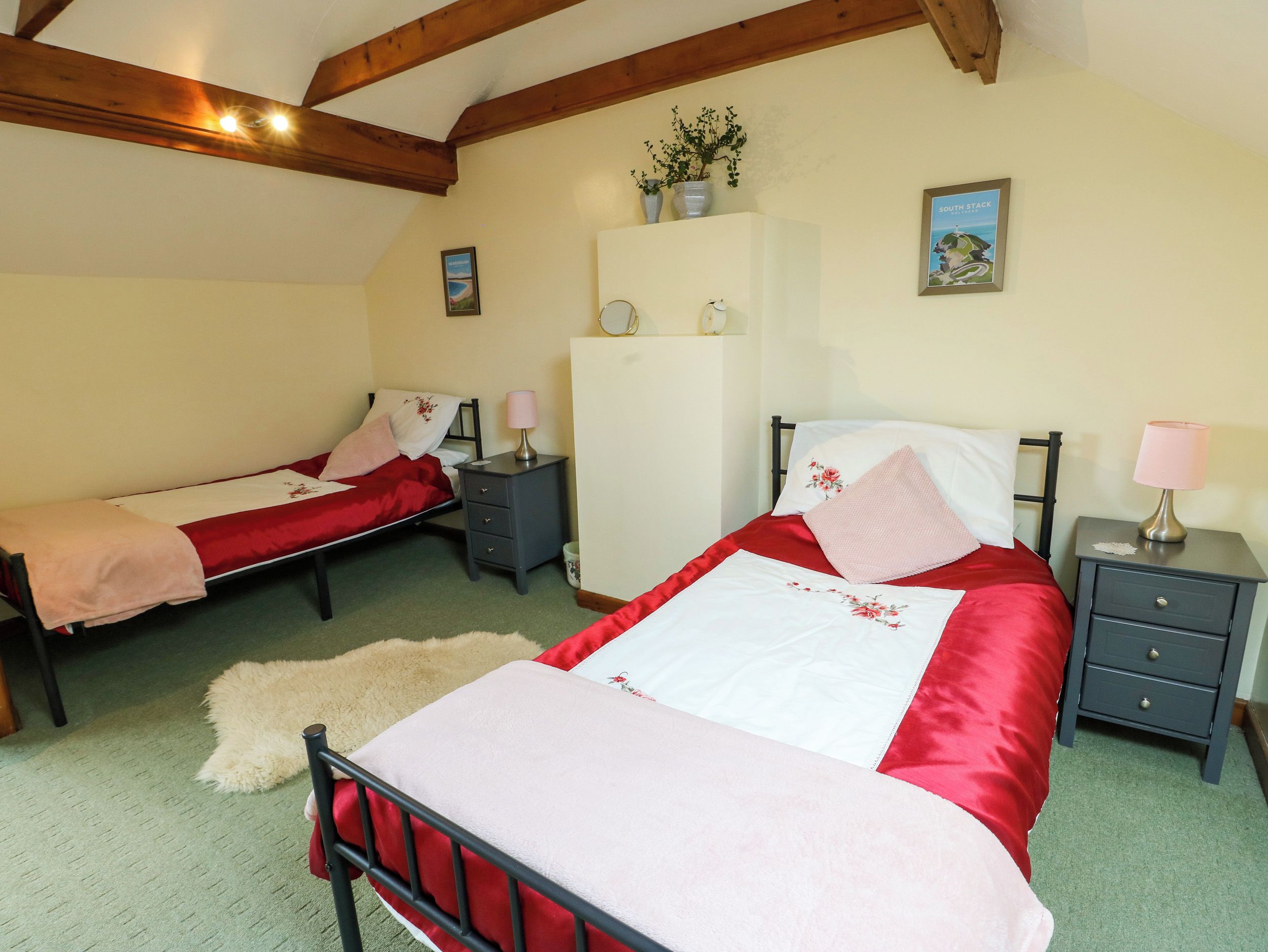 A bedroom with two single beds, a wardrobe, and a nightstand with lamps.