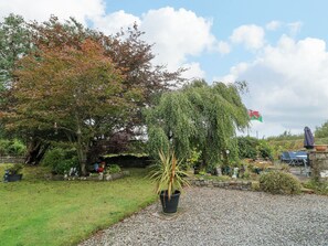 A garden with a variety of trees, a flag, and a seating area.