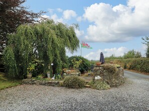 Ein Garten mit einer Trauerweide, einer Steinmauer und einer Flagge.