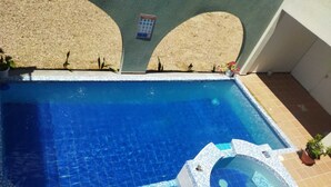 Une piscine rectangulaire dotée d’une plage carrelée et d’un jacuzzi.