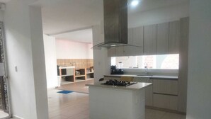 Une cuisine moderne dotée d’un îlot central, d’une cuisinière intégrée et d’une fenêtre laissant entrer la lumière naturelle.