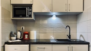 A modern kitchen with a microwave, coffee maker, and a sink. - Apartment next to charming Vistula Boulevards, Pekin (Kraków)