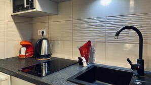 Eine Küche mit Mikrowelle, Wasserkocher, Kaffeemaschine und Spüle.