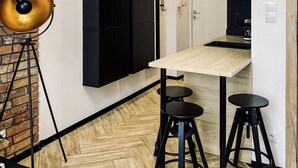 A modern kitchen with a wooden table, black stools, and a brick wall. - Apartment Premium Jacuzzi for couples, Old Town I, Starowiślna (Kraków)